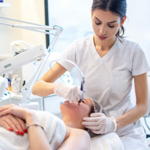 Young woman receiving hydra-facial therapy at beauty salon